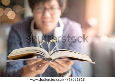 Young Asian happy man holding book with heart shape page folded in the center. love and valentine concepts