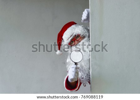 Portrait of Santa claus holding Magnifier in hand after dirty wall,Thailand people,Sent happiness for children,Merry christmas,Welcome to winter