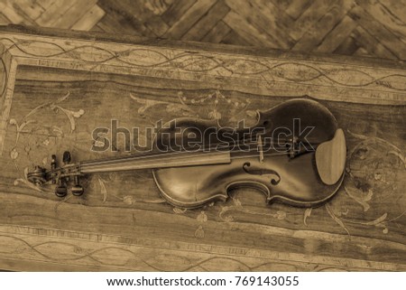 Antique violin on the old incrustated table