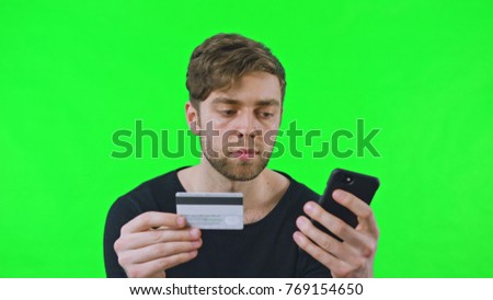 Young man online shoping with bank cards a phone, Dolly shoot, Green Screen. Easy to key out and add your own background.