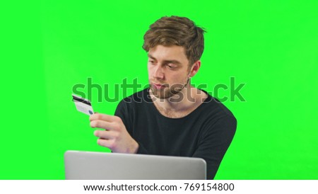 Close-up view of young man online shoping at home on pc, typing credit card number. Dolly shoot, Green Screen. Easy to key out and add your own background.