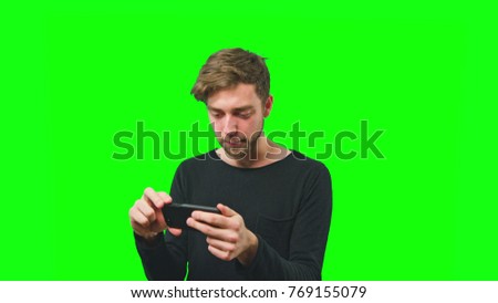 Young man using smart phone playing game, rotate screen on Green Screen Background