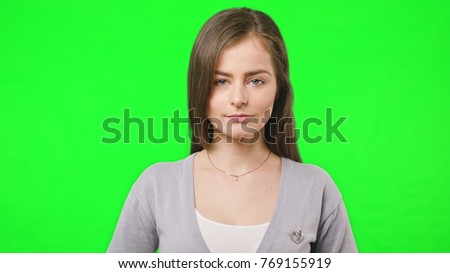 Young pretty girl smiles happily into camera, close up, slow motion over green chroma key screen background