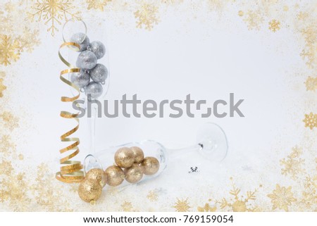 Creative new year celebration concept with champagne glasses on fake snow and golden tinsel