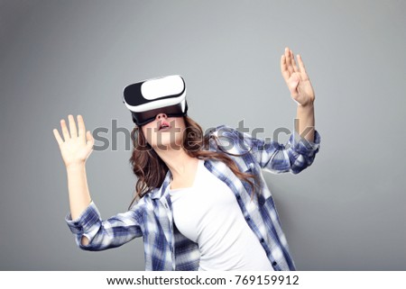 Young girl in virtual reality goggles on grey background