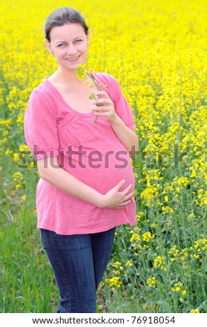 Young attractive pregnant woman enjoying her pregnancy in filed