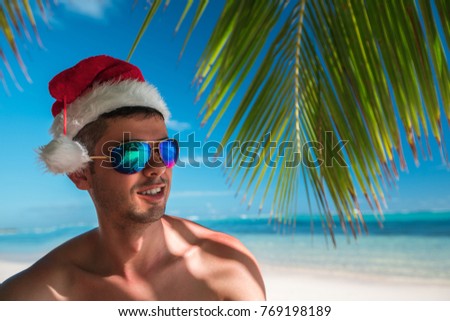 Tourist man with Santa Claus hat relaxing on tropical island beach. Punta Cana, Dominican Republic.