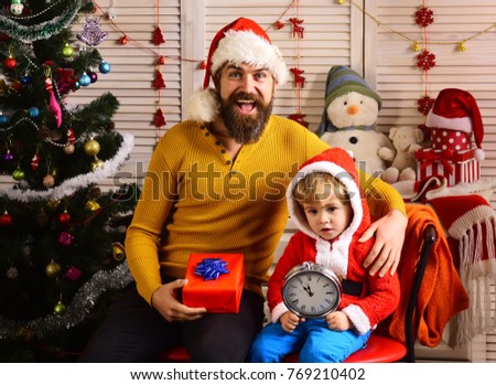 Happy family celebrate new year and Christmas. Father and child with new year gift box and clock. Father and son in santa hat at Christmas tree. Xmas party celebration. Winter holiday and boxing day.