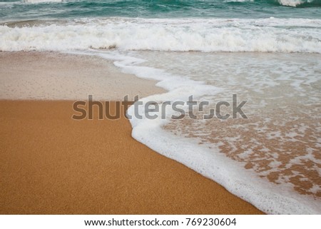 Sea wave and sandy beach. Close up of incoming wave from South China Sea on yellow sandy beach in Sanya.