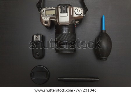 top view of work space photographer with dslr camera system, camera cleaning kit and camera accessory on black table background