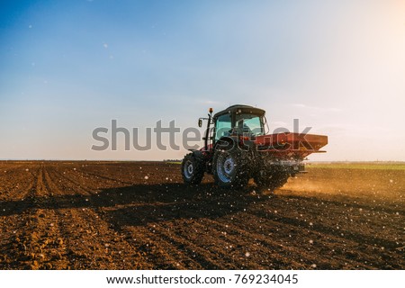 Farmer fertilizing arable land with nitrogen, phosphorus, potassium fertilizer Royalty-Free Stock Photo #769234045
