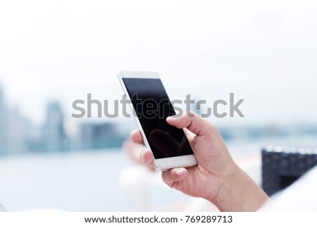 young man plays with mobile phone on balcony in midtown of kuala lumpur in cloud sky 