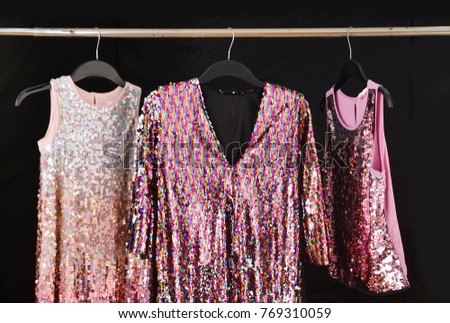 Set of sequins colorful sundress hanging on hanger– black background, 
