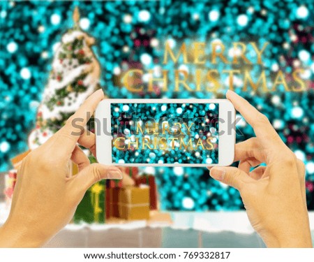 Hand holding smart phone for take photo “Merry Christmas “