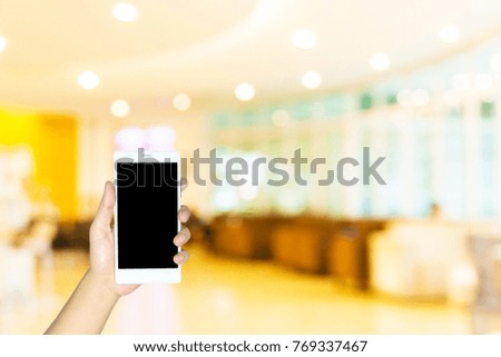 Woman use mobile phone, blur image of beautiful office as background.