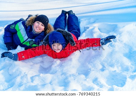Two happy boys sledding from a hill on a sunny winter day. Snow. Winter clothes. Winter activity.