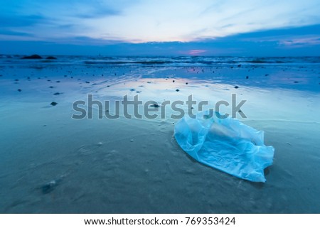 Plastic bag on the beach in the sunrise Royalty-Free Stock Photo #769353424