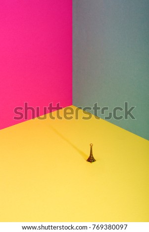 Abstract background of sheets of colored paper with a small figure of the Eiffel Tower