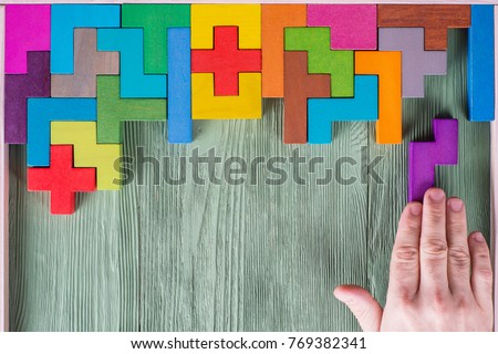 Concept of decision making process, logical thinking. Find the missing piece of the proposed. Hand holding puzzle element. Background with colorful shapes wooden blocks Royalty-Free Stock Photo #769382341