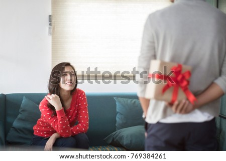 young asian man holding gift for surprise his girlfriend, romantic happy couple sharing gift together on Christmas, happy family concept