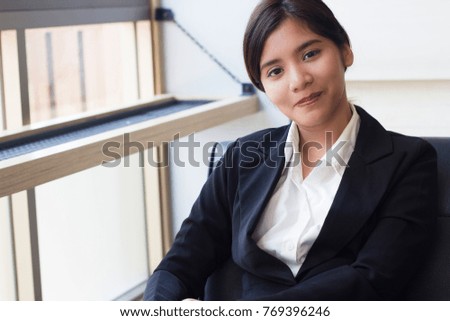 Smiling young Asian business woman looking confident and happy. Copy space.