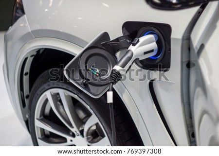  Close up of the Hybrid car electric charger station with power supply plugged into an electric car being charged.