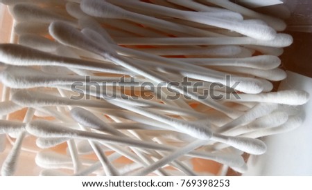 White cotton buds on cream color pastel background.