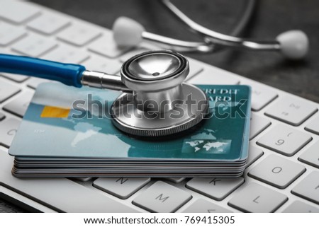 Stethoscope and credit cards on computer keyboard, closeup