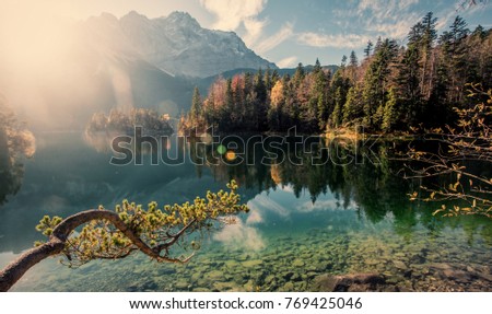 Awesome alpine highlands in sunny day. Nature Landscape. The Eibsee Lake in front of the Zugspitze under sunlight reflected in water. Majestic Autumn Scenery.  Eibsee, Bavaria Germany. Retro Style