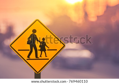School zone warning sign on blur traffic road with colorful bokeh light abstract background. Copy space of transportation and travel concept. Vintage tone filter effect color style.