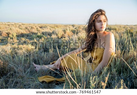 Young woman sitting, alone in nature.
