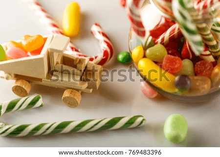 Festive mess on the table. toys and candy. White glossy table. The candy jar.