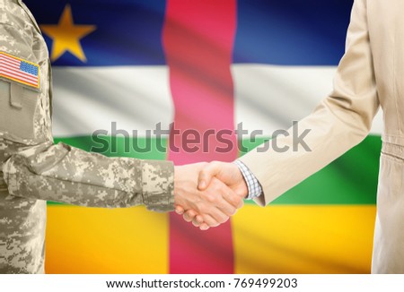 American soldier in uniform and civil man in suit shaking hands with adequate national flag on background - Central African Republic