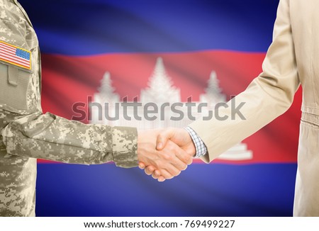 American soldier in uniform and civil man in suit shaking hands with adequate national flag on background - Cambodia