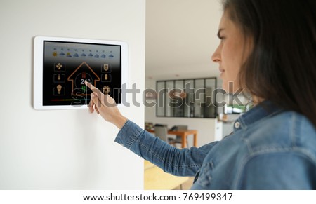 Woman using smart wall home control system  Royalty-Free Stock Photo #769499347