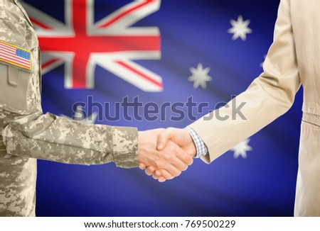 American soldier in uniform and civil man in suit shaking hands with adequate national flag on background - Australia