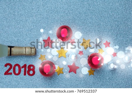 Spray of the stars and Christmas tree balls from a bottle of champagne on a silver background. The time of Christmas and New Year's magic.

