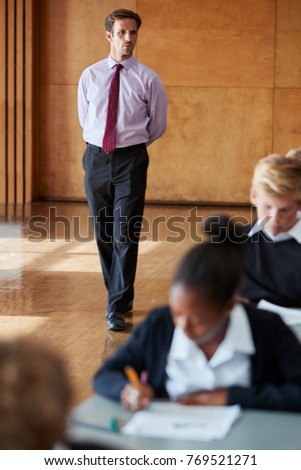 Teenage Students Sitting Examination With Teacher Invigilating Royalty-Free Stock Photo #769521271