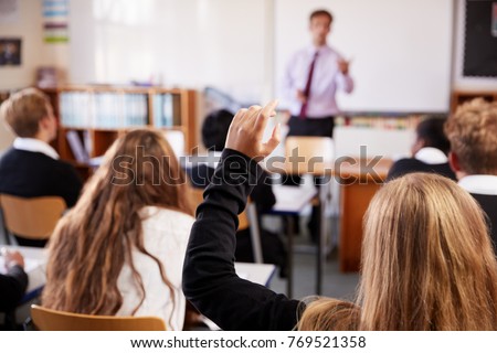 Female Student Raising Hand To Ask Question In Classroom Royalty-Free Stock Photo #769521358