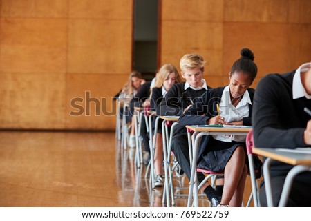 Teenage Students In Uniform Sitting Examination In School Hall Royalty-Free Stock Photo #769522759
