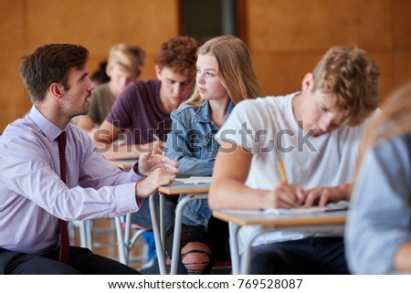Teenage Students Sitting Examination With Teacher Invigilating Royalty-Free Stock Photo #769528087