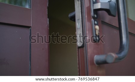 A man open the door and comes out of the building. Close-up shot.