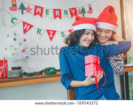 Two asian women Lesbian couple holding gift box in christmas party, Have christmas tree ornaments.