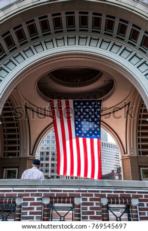 US Veteran looking at Big US american Stars Stripes Flag Hanging from inside Dome in Boston Massachusetts on sunny day