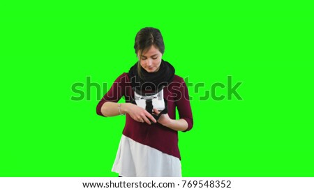 Young woman with VR virtual reality headset on her head, green screen