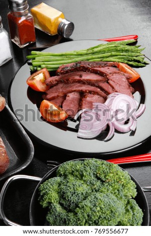 business lunch fresh roast beef meat slices on black plate wotj cutlery asparagus boiled broccoli rye bun on wooden table