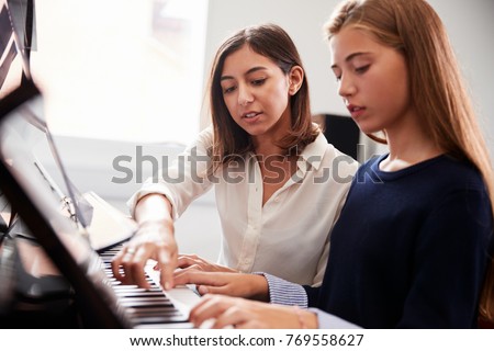 Female Pupil With Teacher Playing Piano In Music Lesson Royalty-Free Stock Photo #769558627