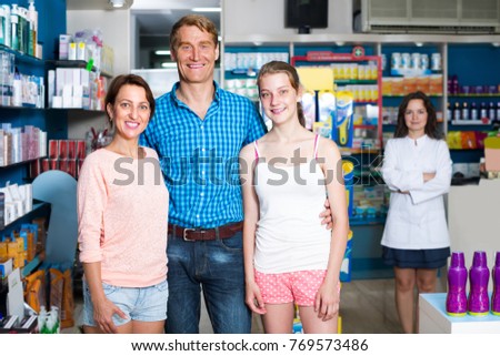 smiling parents with teenager daughter buying goods in pharmaceutical store 
