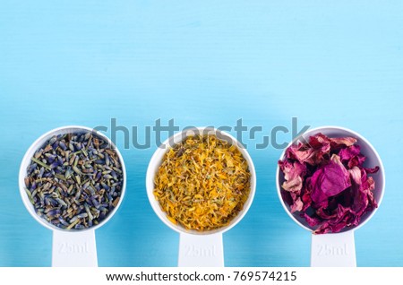 Plastic scoops with various healing herbs - dry marigold, lavender and dog rose flowers. Aromatherapy, herbal medicine and natural skin care concept. Top view, copy space.