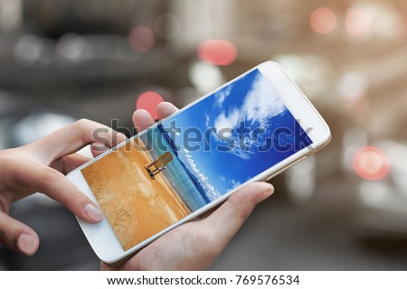 woman hand hold and touch screen with tropical spring summer beach solution concept on smartphone or cellphone over blurred urban city traffic background,image for booking travel holiday concept.